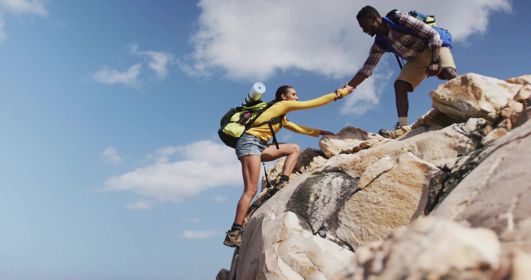 Hikers helping each other up a summit